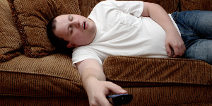Man asleep on the couch, with TV remote control firmly in hand.